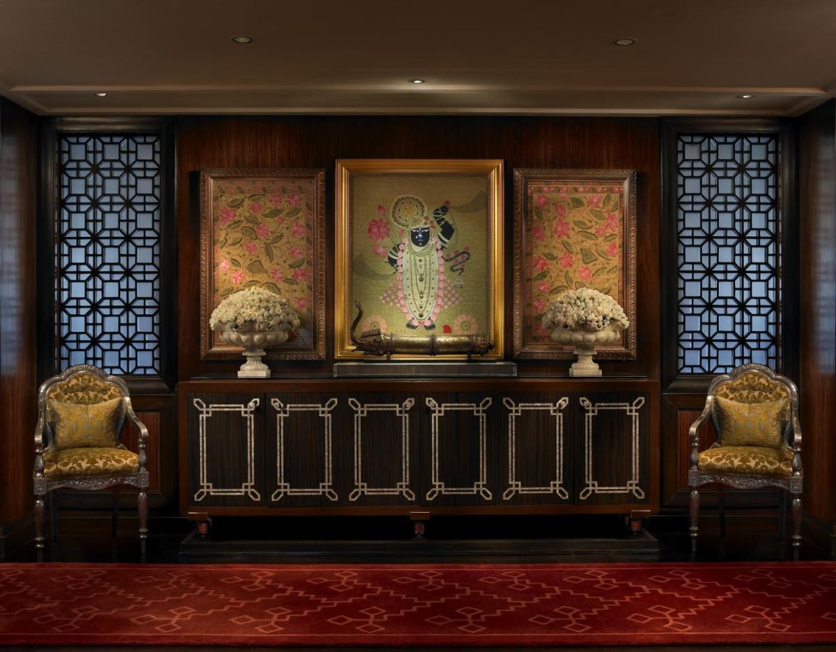 a room with three chairs and paintings on a wall at The Leela Palace Udaipur in Udaipur