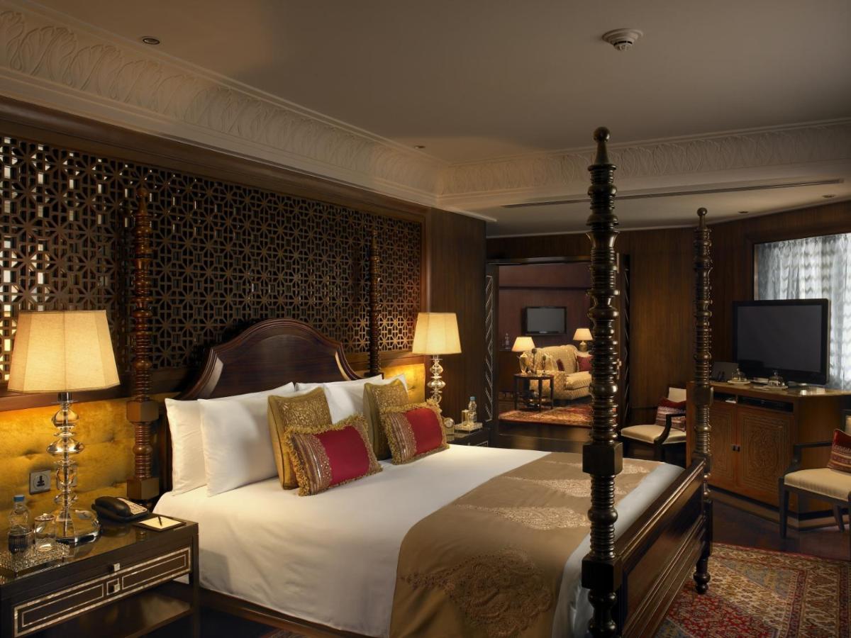 a bedroom with a large bed and a television at The Leela Palace Udaipur in Udaipur a bedroom with a large bed and a television at The Leela Palace Udaipur in Udaipur