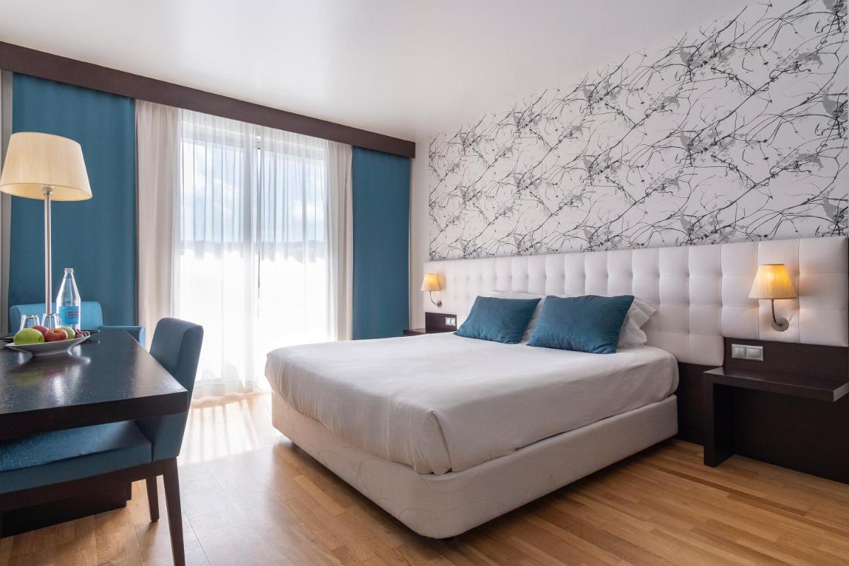 um quarto com uma grande cama branca e uma escrivaninha em Hotel Vale Do Navio em Capelas mais 25 fotografias