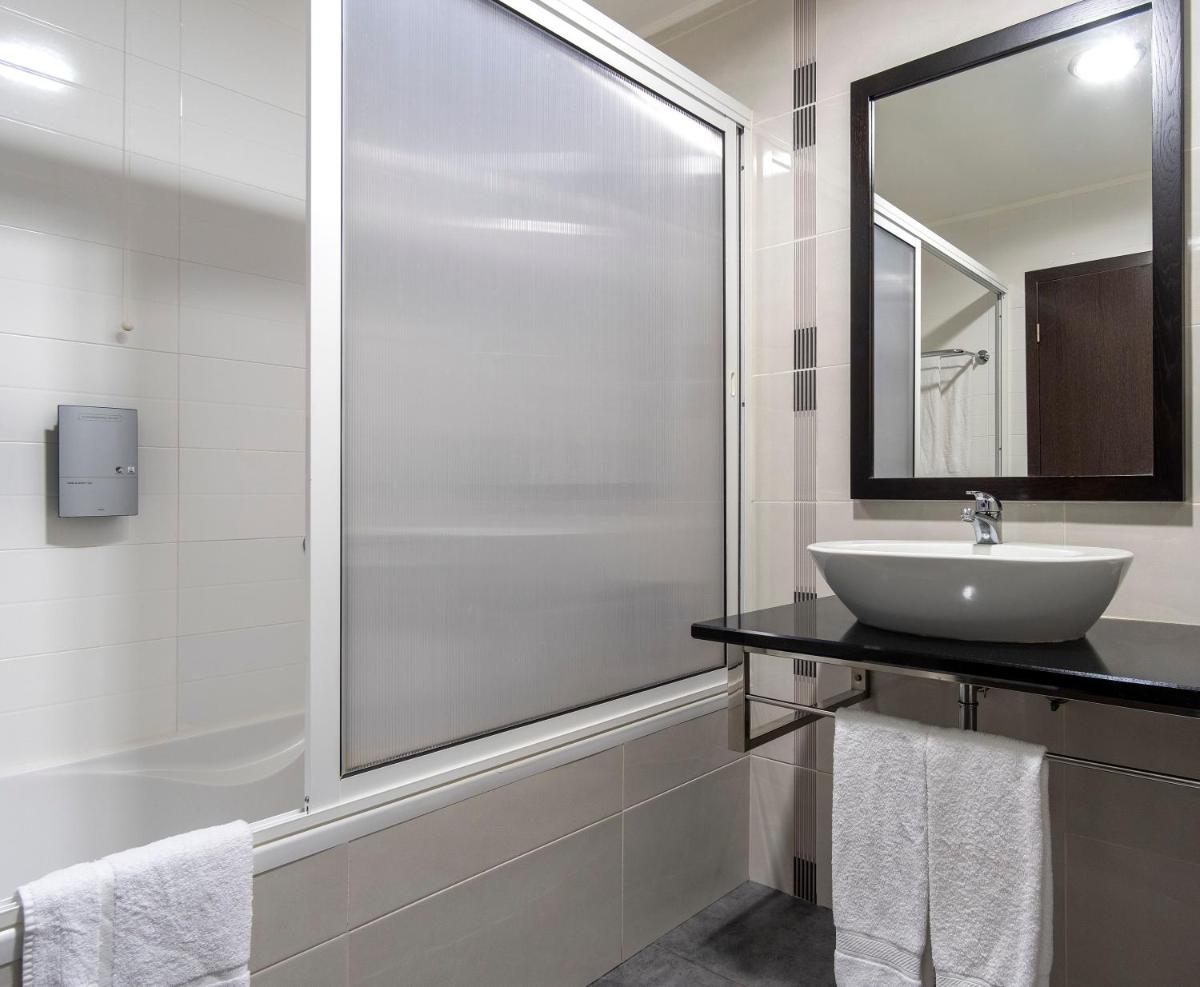 um banheiro branco com uma pia e um chuveiro em Hotel Vale Do Navio em Capelas