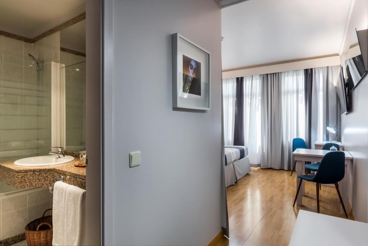 um quarto com uma casa de banho com um lavatório e uma mesa em Sé Boutique Hotel no Funchal