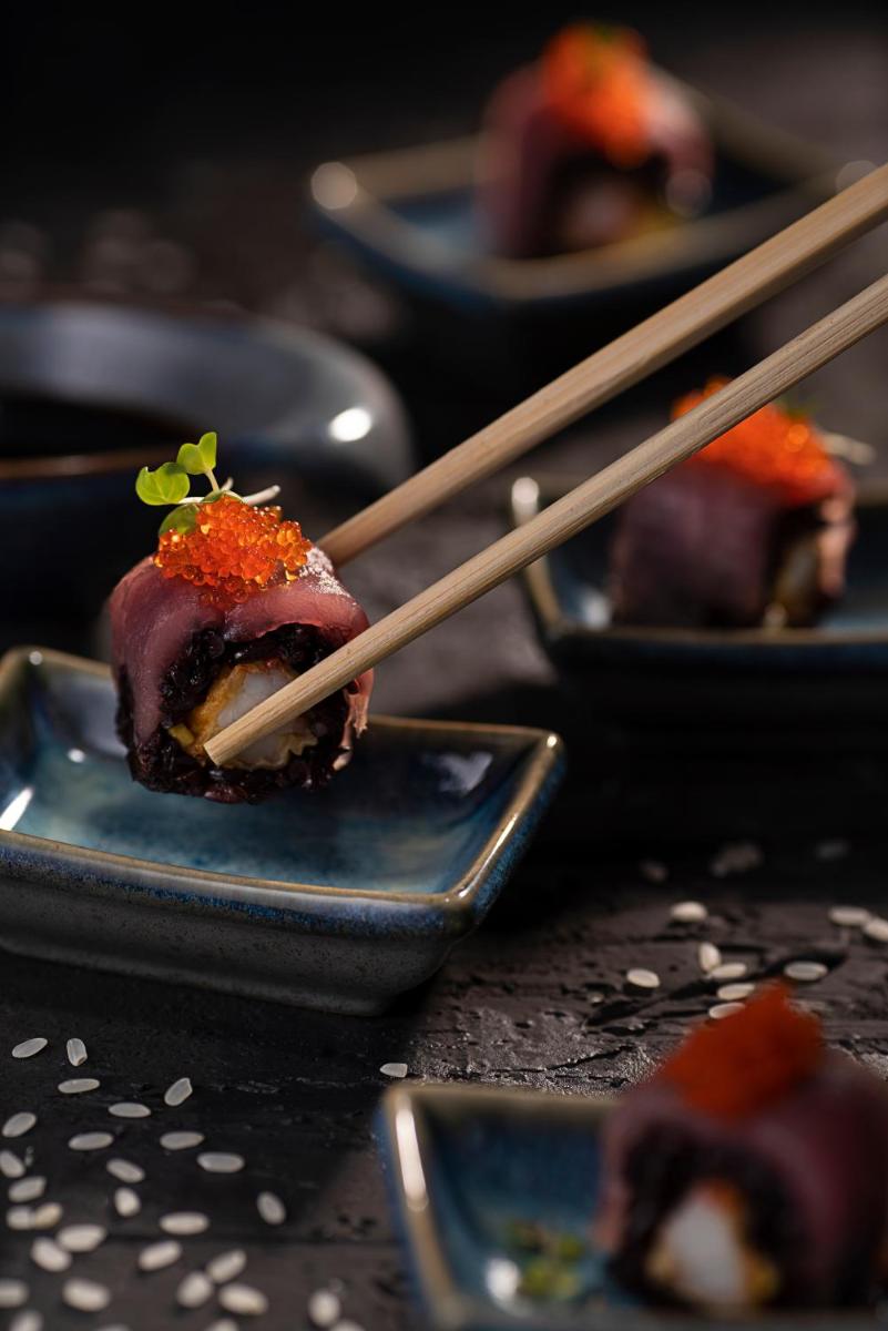 a piece of sushi on a plate with chopsticks at Novotel Chennai Chamiers Road in Chennai