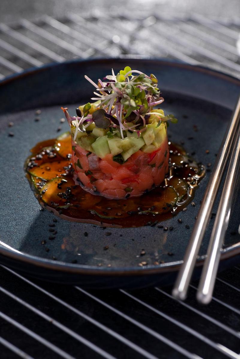 a black plate with a food item on a grill at Novotel Chennai Chamiers Road in Chennai