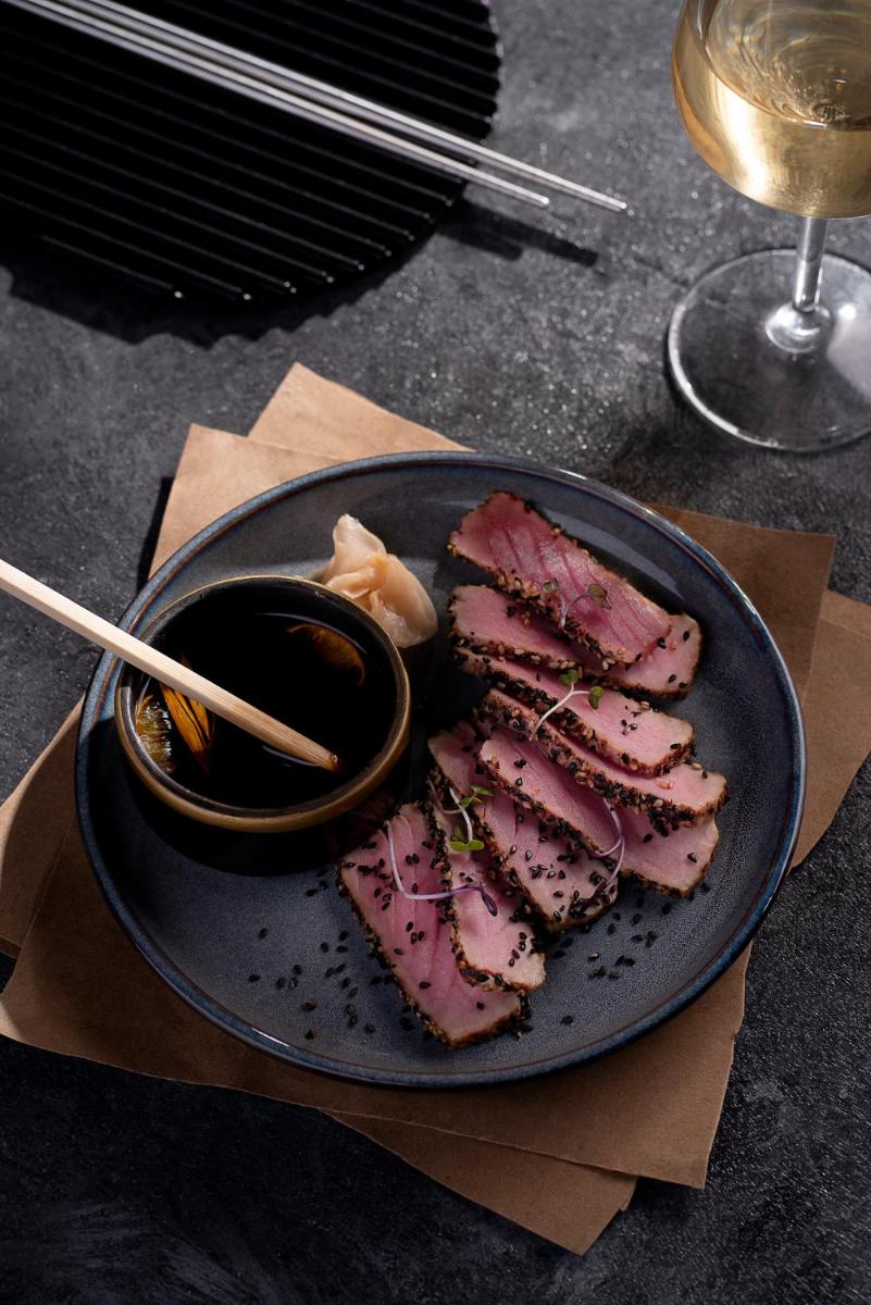 a plate of meat with chopsticks and a bowl of sauce at Novotel Chennai Chamiers Road in Chennai