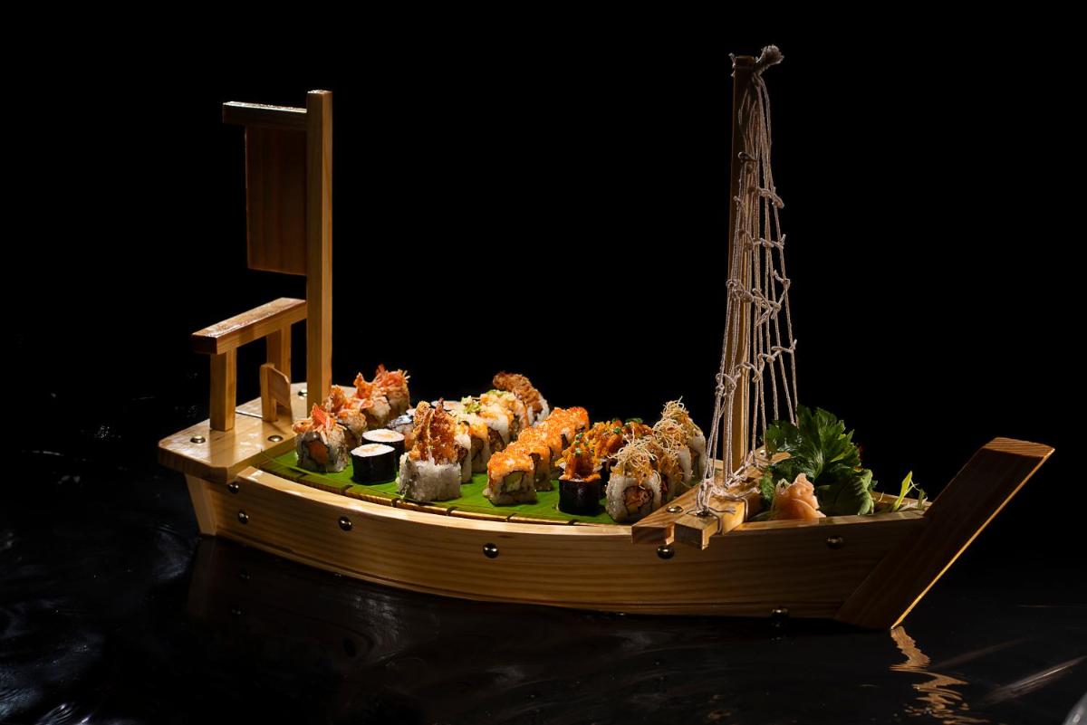 a wooden boat with sushi on top of the water at Novotel Chennai Chamiers Road in Chennai