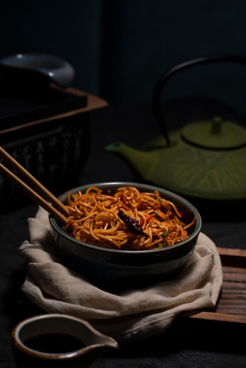 a bowl of noodles with chopsticks sitting on a table at Novotel Chennai Chamiers Road in Chennai