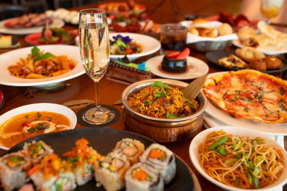 a table with plates of food and a glass of wine at Novotel Chennai Chamiers Road in Chennai
