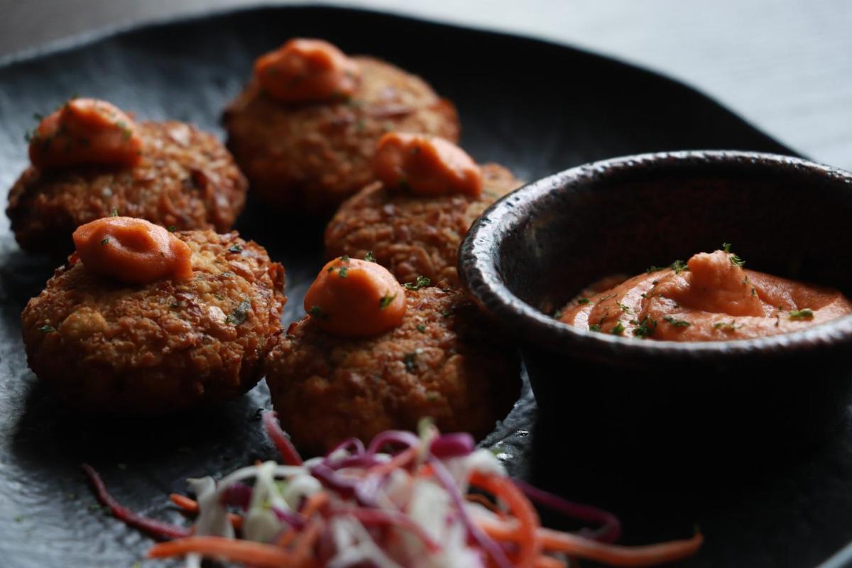 a plate of meatballs with a bowl of dipping sauce at Novotel Chennai Chamiers Road in Chennai