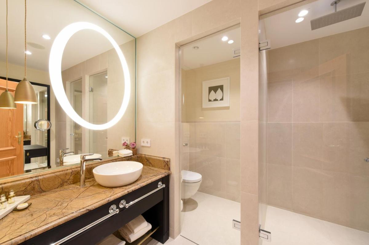 ein Badezimmer mit Waschbecken, Toilette und Spiegel in der Unterkunft Hotel Landhaus Wachtelhof in Rotenburg an der Wümme