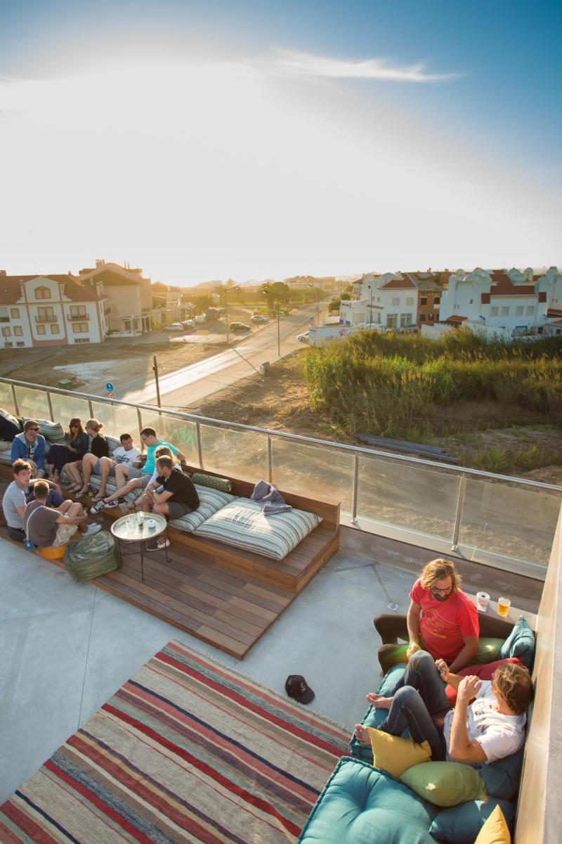 um grupo de pessoas sentadas em sofás numa varanda em Surfers Lodge Peniche em Peniche