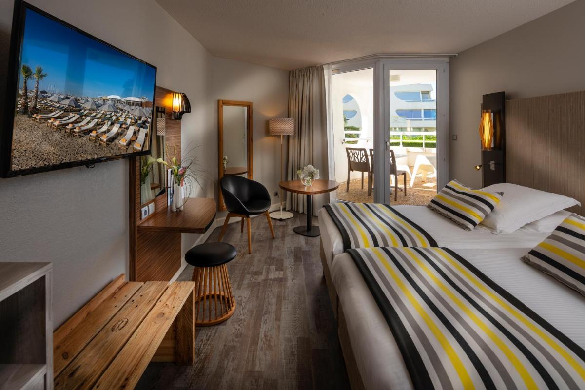 une chambre d'hôtel avec un lit et une télévision dans l'établissement Thalazur Port-Camargue - Hotel & Spa, au Grau-du-Roi