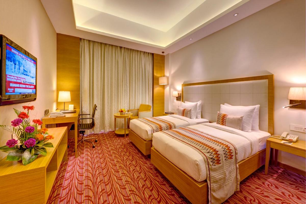 a hotel room with two beds and a television at Pride Plaza Hotel, Kolkata in Kolkata