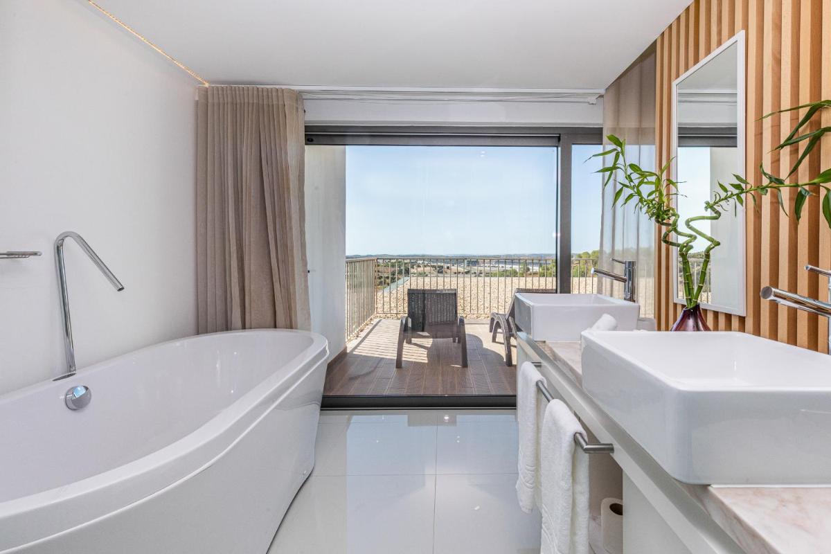 uma casa de banho com 2 lavatórios e uma banheira com vista em Algarve Race Resort - Hotel em Montes de Cima