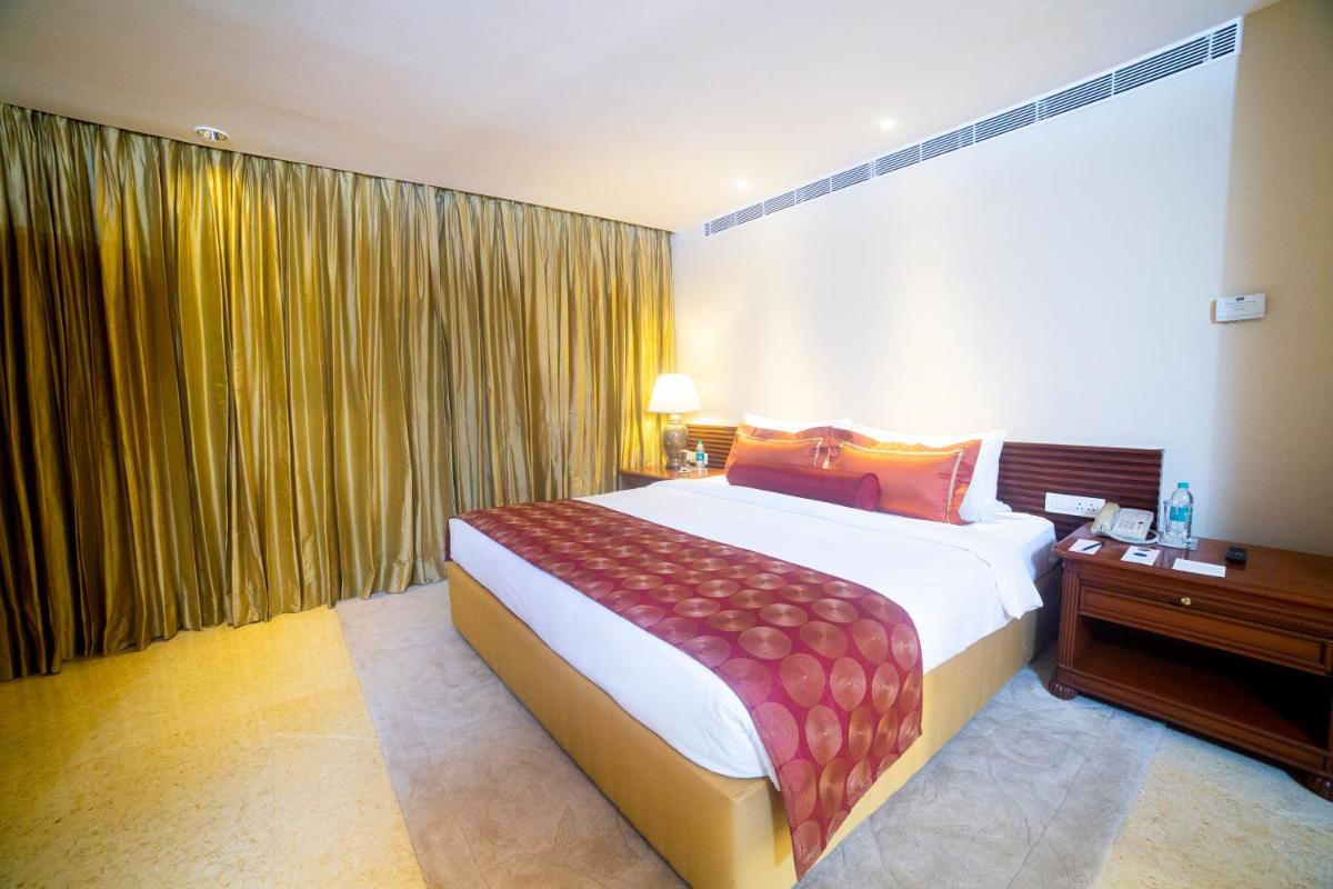 a bedroom with a large bed and a large window at Taj Club House in Chennai