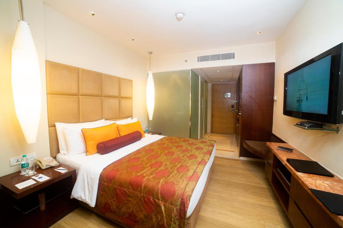 a hotel room with a large bed and a flat screen tv at Taj Club House in Chennai