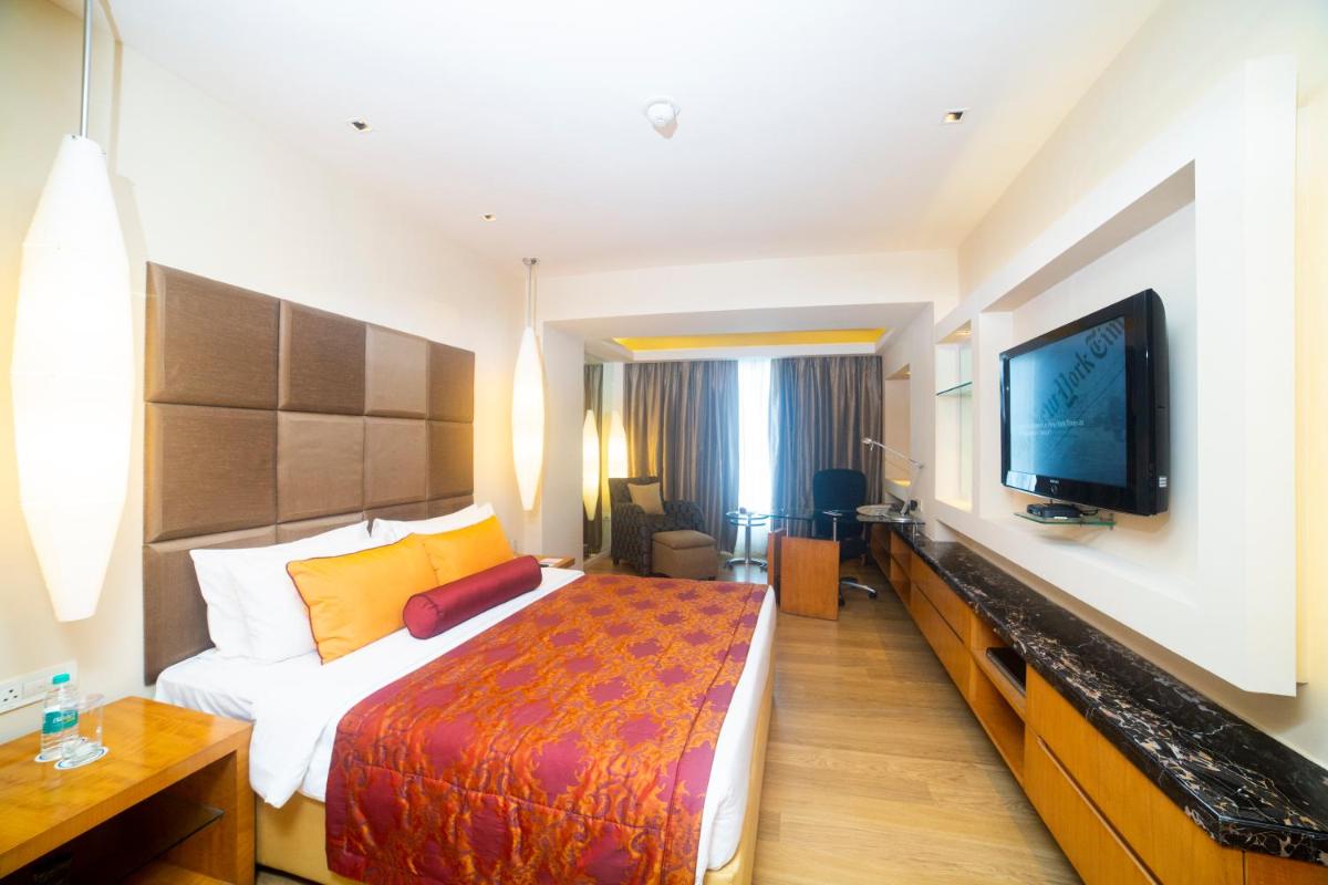a hotel room with a bed and a flat screen tv at Taj Club House in Chennai