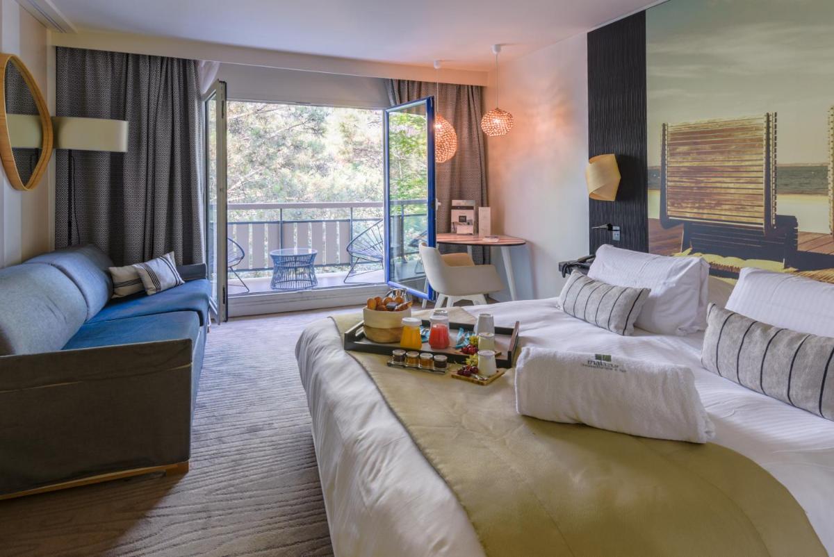 une chambre d'hôtel avec un grand lit et un canapé dans l'établissement Thalazur Arcachon, à Arcachon