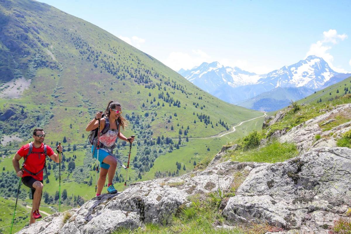 Deux personnes font de la randonnée sur une montagne. dans l'établissement Hôtel Au Chamois d'Or by Les Etincelles, à L'Alpe-d'Huez