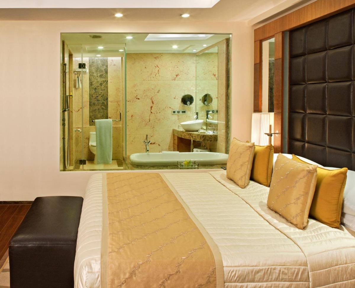 a bedroom with a large bed and a bath tub at Radisson Blu Plaza Delhi Airport in New Delhi a bedroom with a large bed and a bath tub at Radisson Blu Plaza Delhi Airport in New Delhi