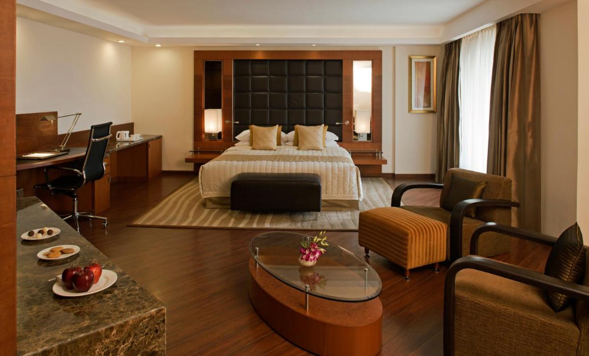 a hotel room with a bed and a living room at Radisson Blu Plaza Delhi Airport in New Delhi a hotel room with a bed and a living room at Radisson Blu Plaza Delhi Airport in New Delhi