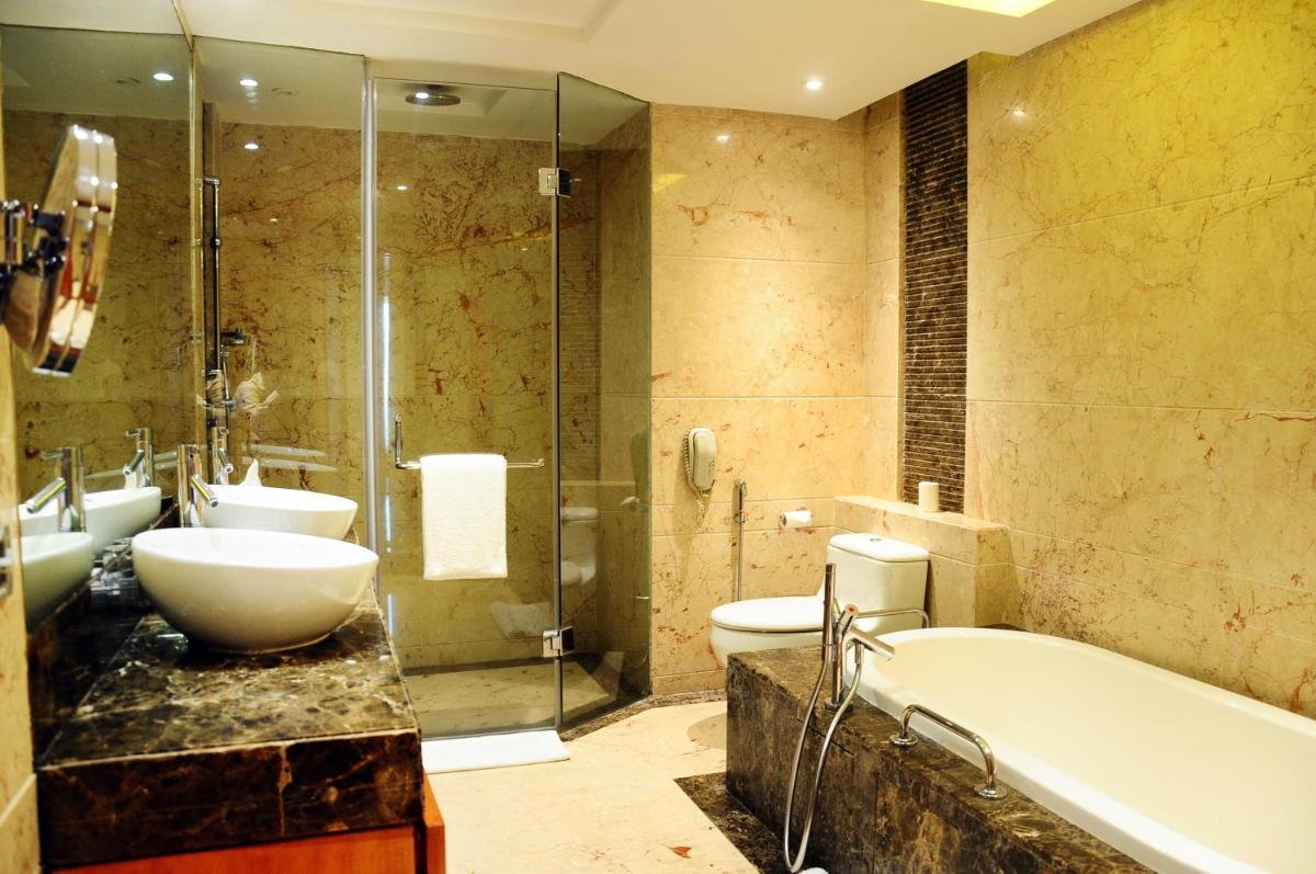 a bathroom with a tub and a toilet and a sink at Radisson Blu Plaza Delhi Airport in New Delhi a bathroom with a tub and a toilet and a sink at Radisson Blu Plaza Delhi Airport in New Delhi