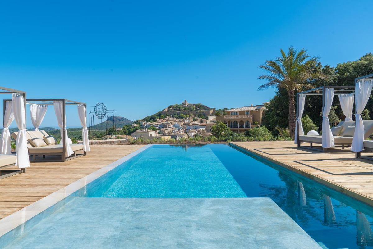 una piscina con sillas blancas junto a un complejo en Hotel Creu de Tau Art&Spa-Adults only, en Capdepera