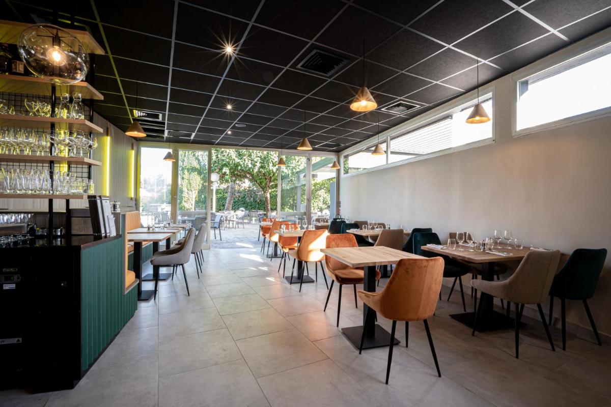 une salle à manger avec tables, chaises et fenêtres dans l'établissement PoMo Hôtel & Restaurant, à Échirolles