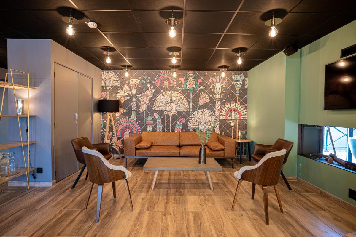 un salon avec un canapé, une table et des chaises dans l'établissement PoMo Hôtel & Restaurant, à Échirolles
