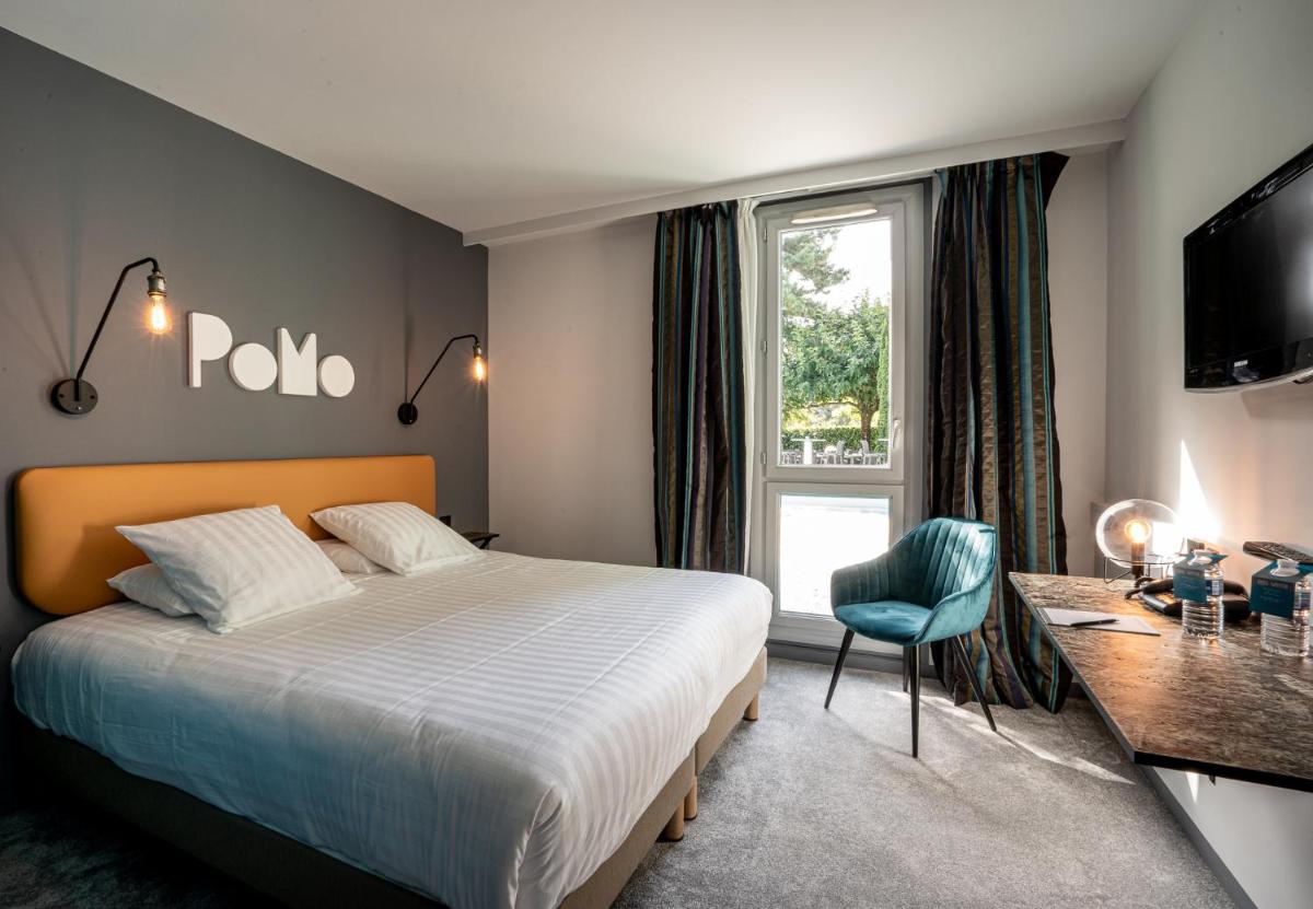 une chambre avec un lit, un bureau et une fenêtre dans l'établissement PoMo Hôtel & Restaurant, à Échirolles