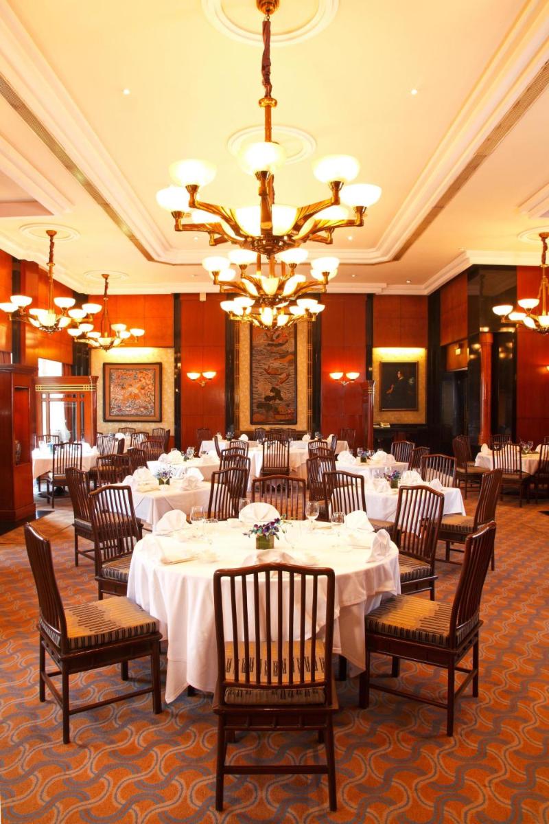 a dining room with tables and chairs and a chandelier at Eros Hotel New Delhi, Nehru Place in New Delhi a dining room with tables and chairs and a chandelier at Eros Hotel New Delhi, Nehru Place in New Delhi