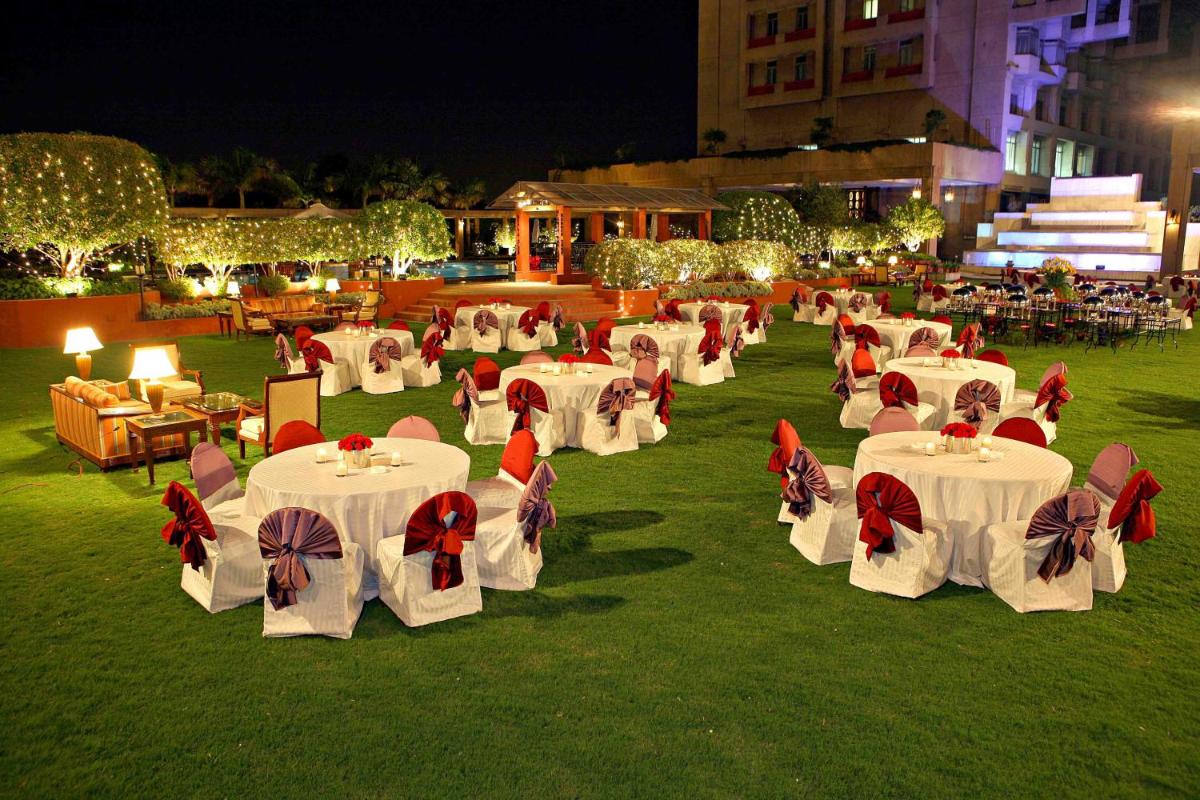a group of tables and chairs on a lawn at night at Eros Hotel New Delhi, Nehru Place in New Delhi a group of tables and chairs on a lawn at night at Eros Hotel New Delhi, Nehru Place in New Delhi
