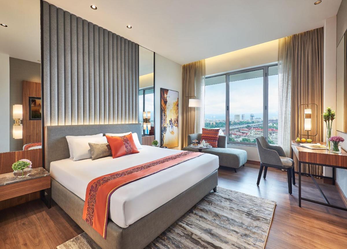 a hotel room with a large bed and a desk at Vivanta Kolkata EM Bypass in Kolkata