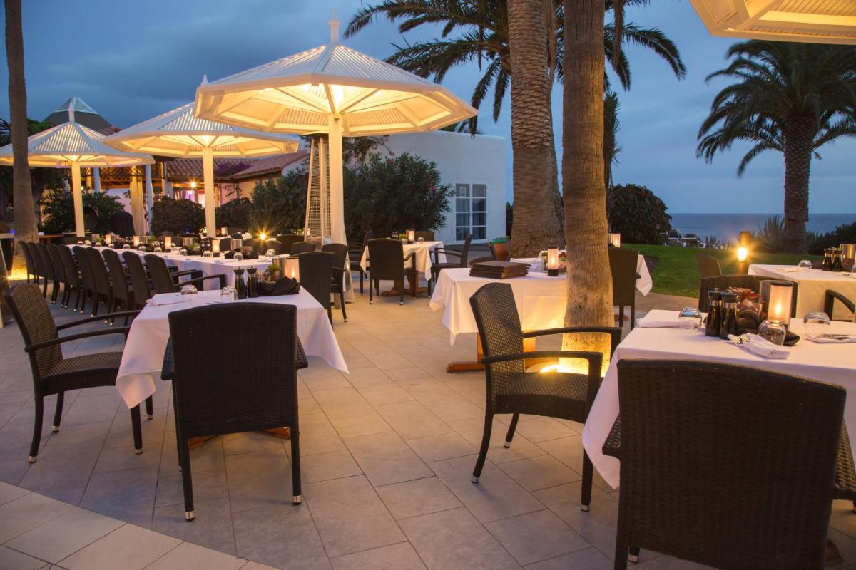 Un restaurante con mesas y sombrillas en un patio. en ROBINSON ESQUINZO PLAYA - All Inclusive, en Morro del Jable