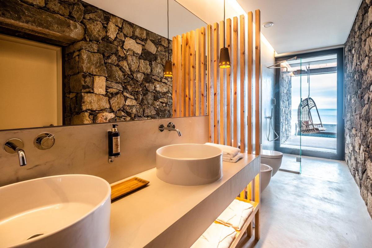 uma casa de banho com 2 lavatórios e uma parede de pedra em SENSI Azores Nature and SPA em Ginetes