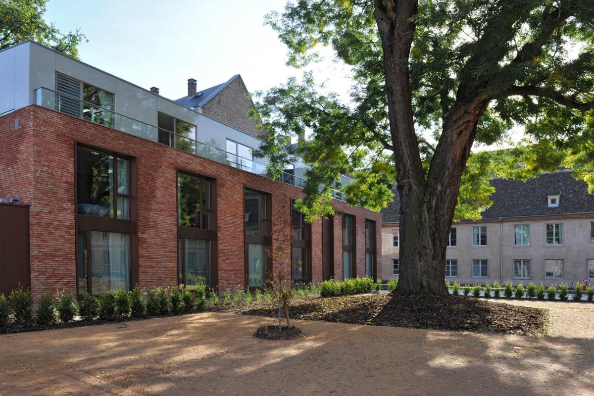 un bâtiment en briques avec un arbre devant lui dans l'établissement Hotel Les Haras, à Strasbourg