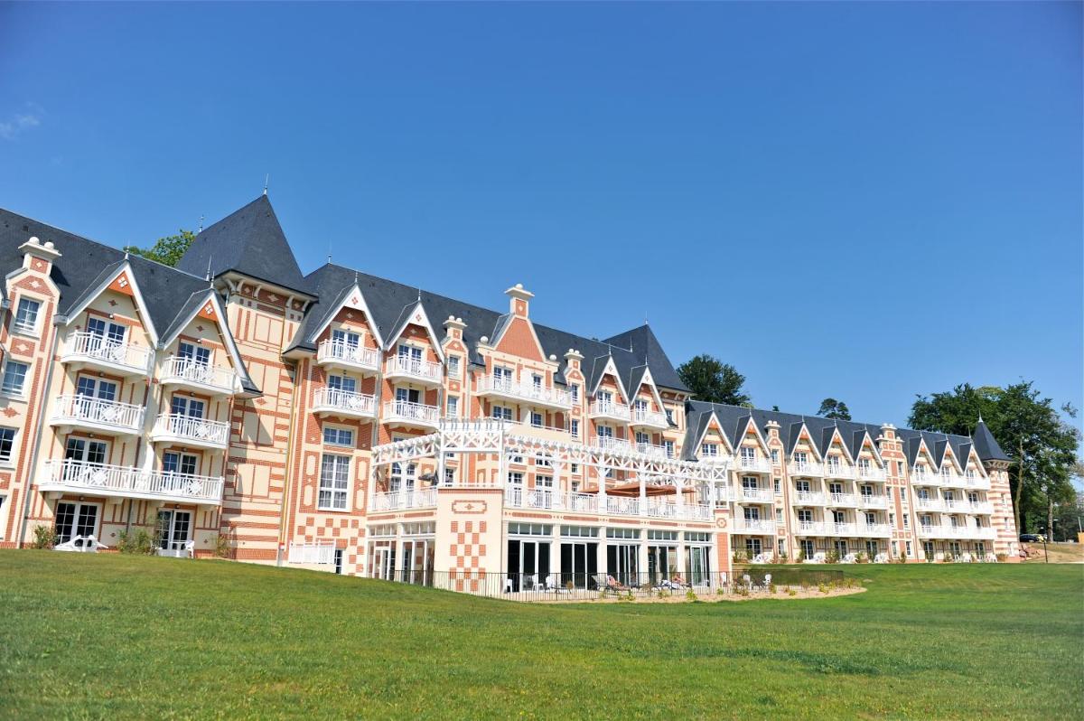 - un grand bâtiment au-dessus d'un champ verdoyant dans l'établissement Résidence b'o cottage - b'o resort thermal & spa, à Bagnoles-de-l'Orne