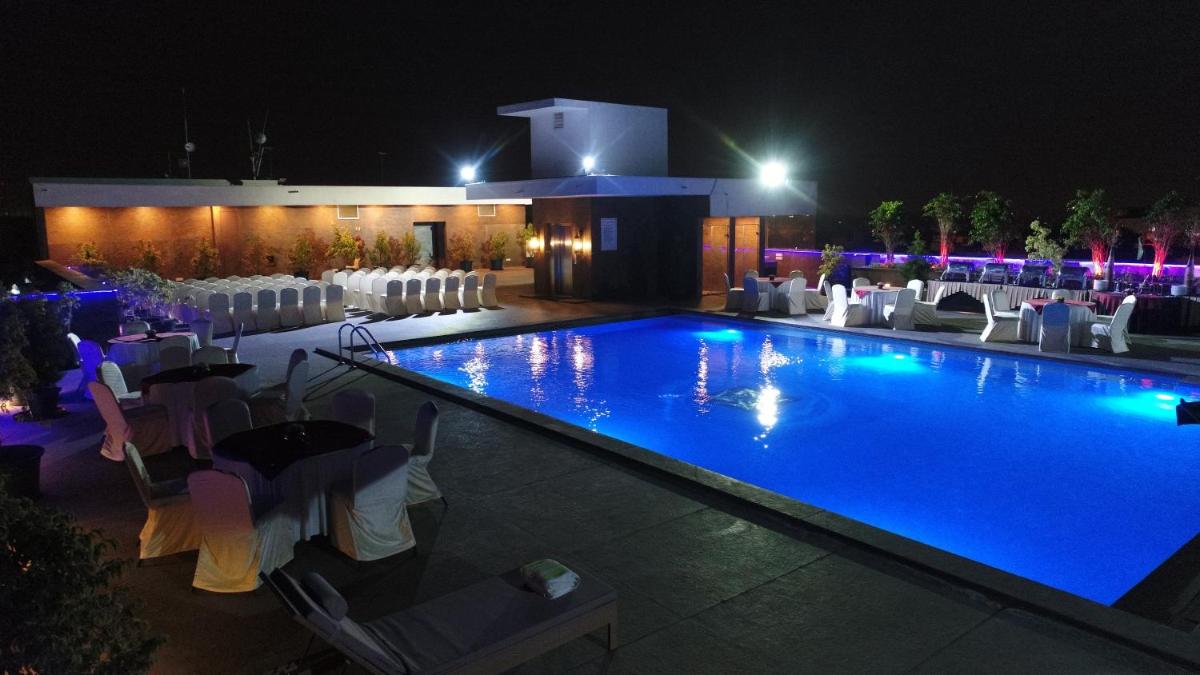 a swimming pool at night with tables and chairs at La Marvella, Bengaluru in Bengaluru a swimming pool at night with tables and chairs at La Marvella, Bengaluru in Bengaluru