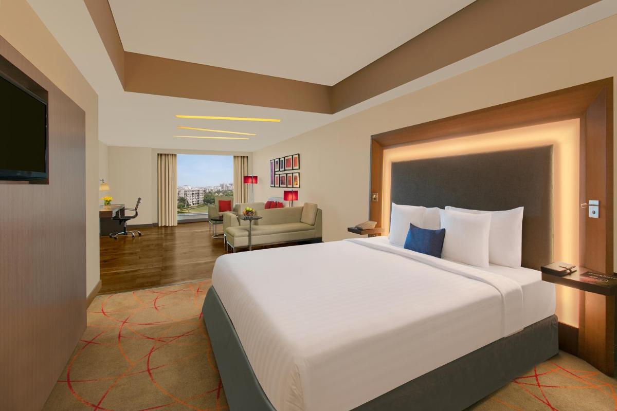 a hotel room with a large bed and a living room at Novotel Ahmedabad in Ahmedabad