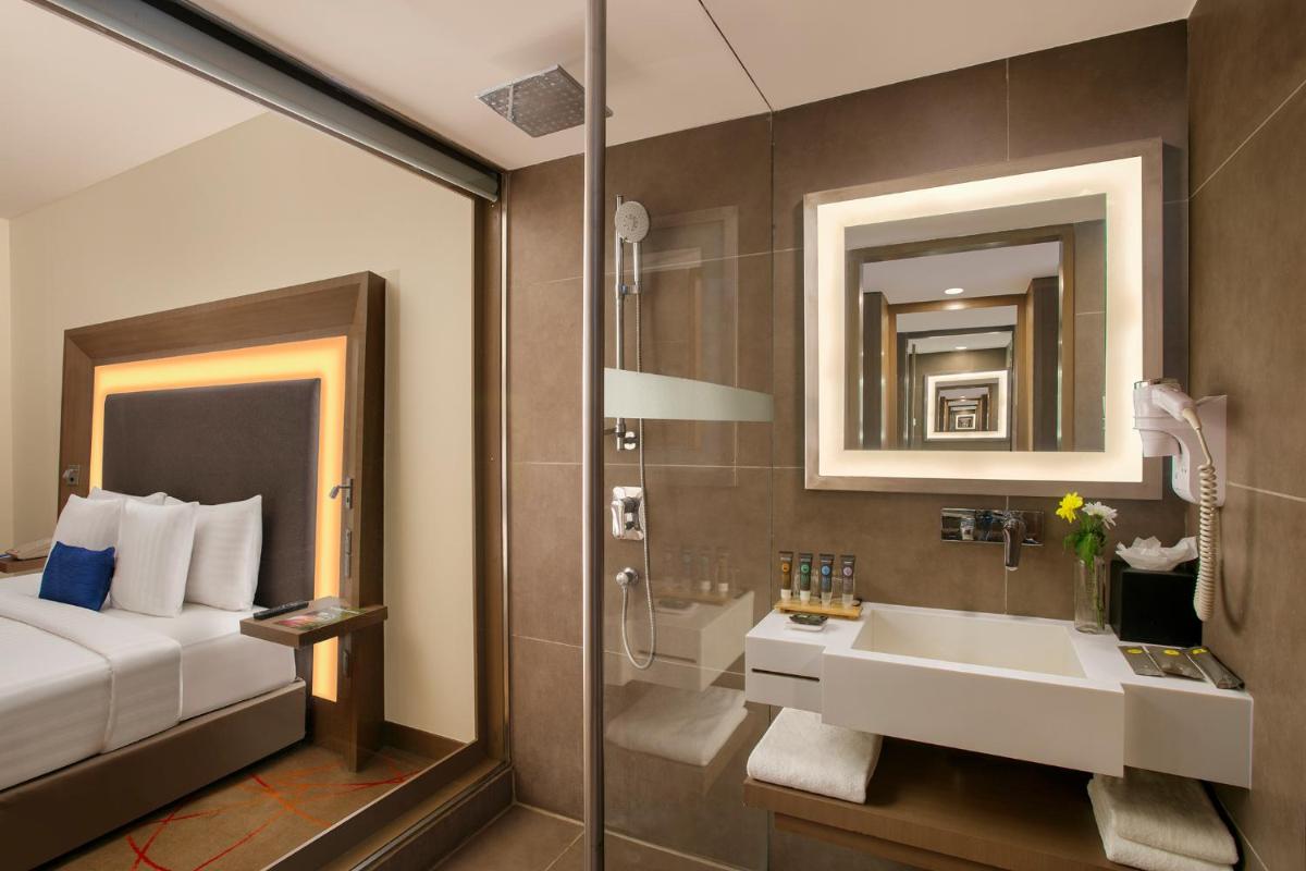 a bathroom with a bed and a sink and a shower at Novotel Ahmedabad in Ahmedabad