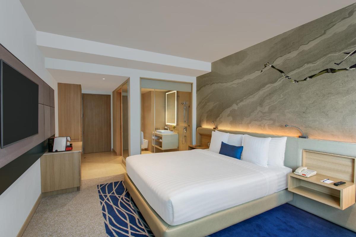 a hotel room with a large bed and a television at Novotel Ahmedabad in Ahmedabad