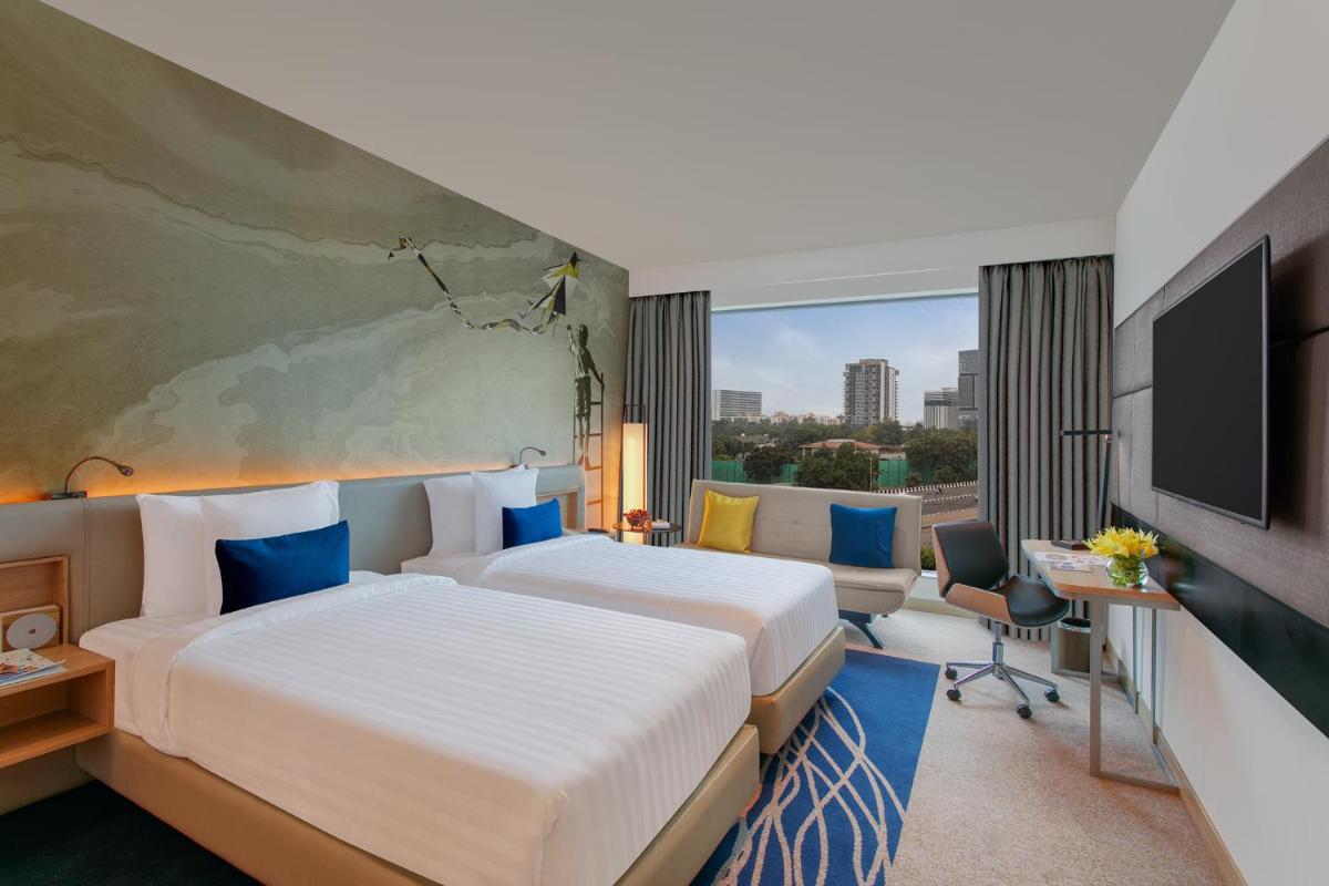 a hotel room with two beds and a flat screen tv at Novotel Ahmedabad in Ahmedabad