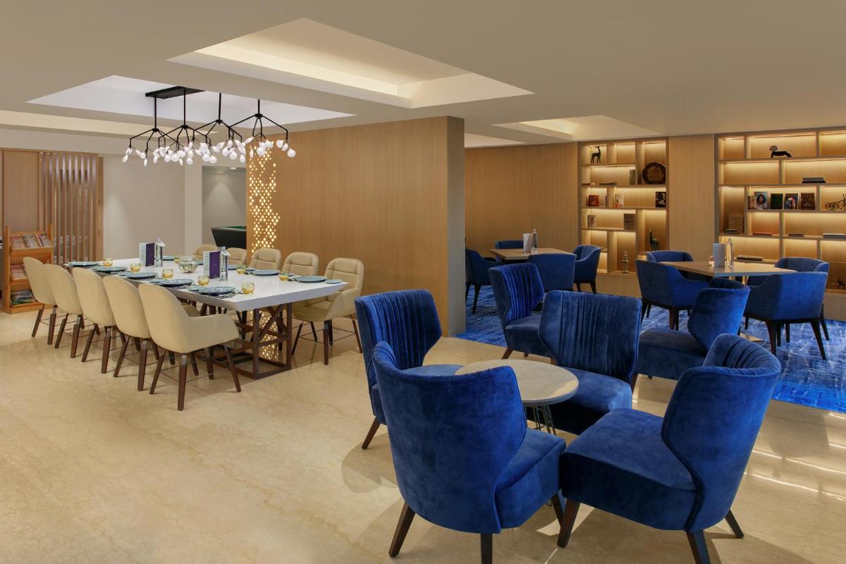 a dining room with blue chairs and a table andools at Novotel Ahmedabad in Ahmedabad