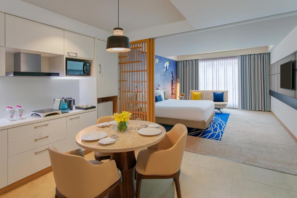 a hotel room with a kitchen and a table with chairs at Novotel Ahmedabad in Ahmedabad