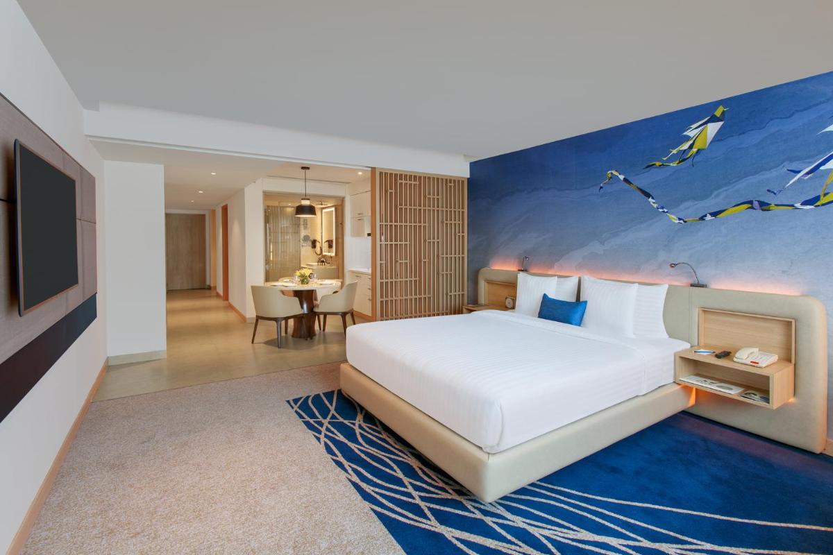 a bedroom with a large bed with a painting on the wall at Novotel Ahmedabad in Ahmedabad