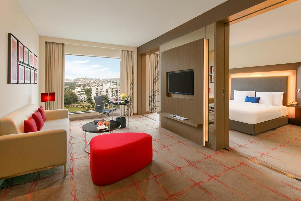 a large hotel room with a bed and a tv at Novotel Ahmedabad in Ahmedabad