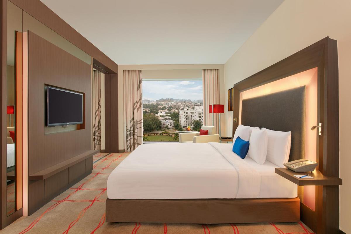 a hotel room with a large bed and a television at Novotel Ahmedabad in Ahmedabad