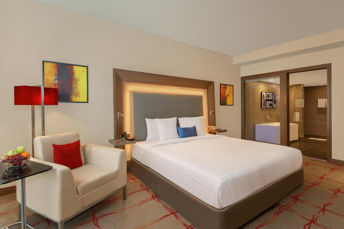 a bedroom with a large bed and a chair at Novotel Ahmedabad in Ahmedabad