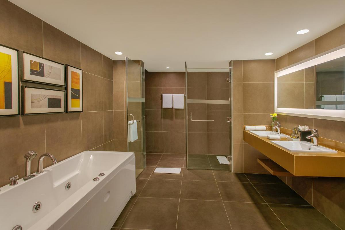 a bathroom with a tub and two sinks and a shower at Novotel Ahmedabad in Ahmedabad