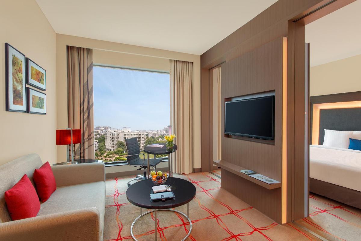 a hotel room with a bed and a tv at Novotel Ahmedabad in Ahmedabad