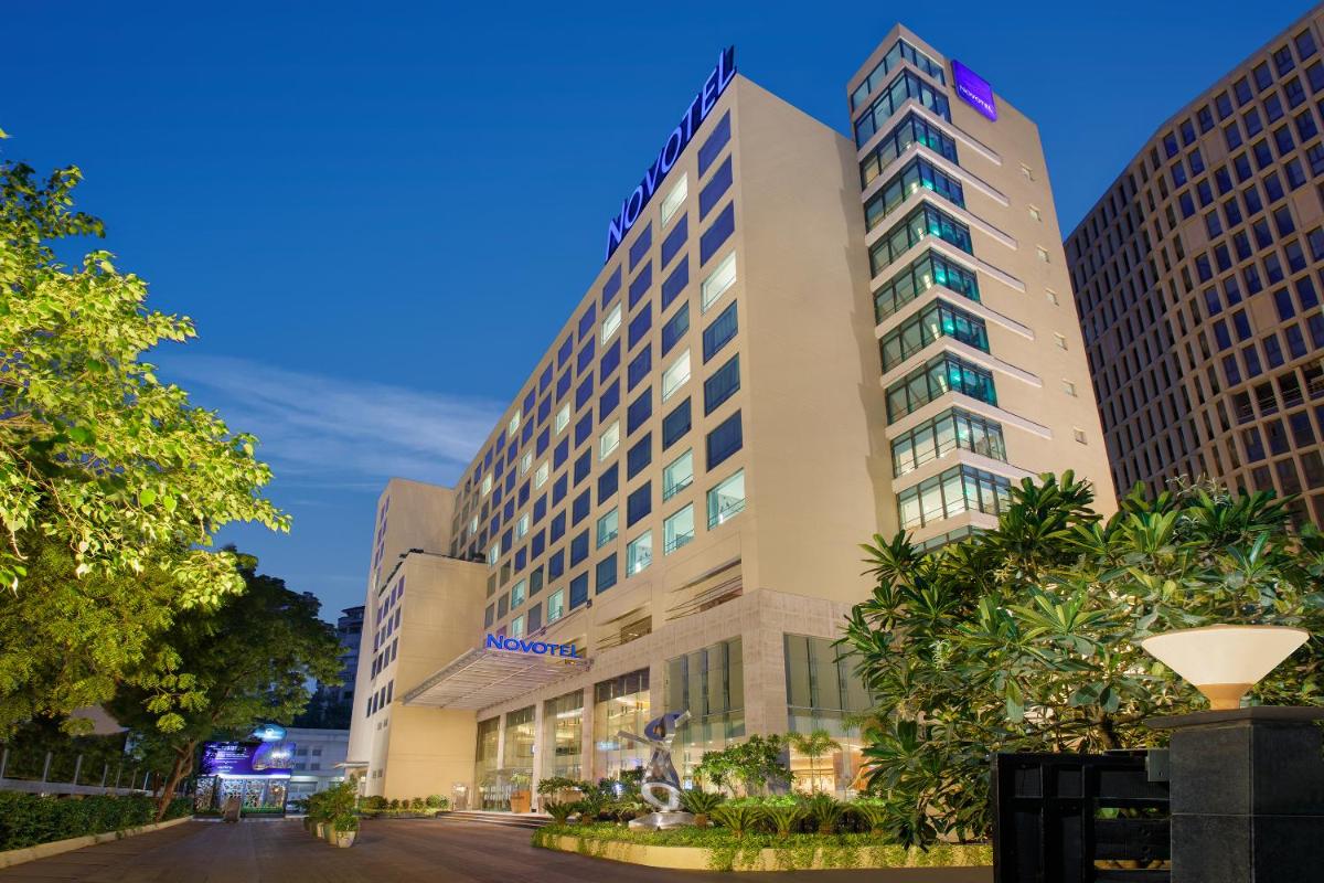 a tall building with trees in front of it at Novotel Ahmedabad in Ahmedabad